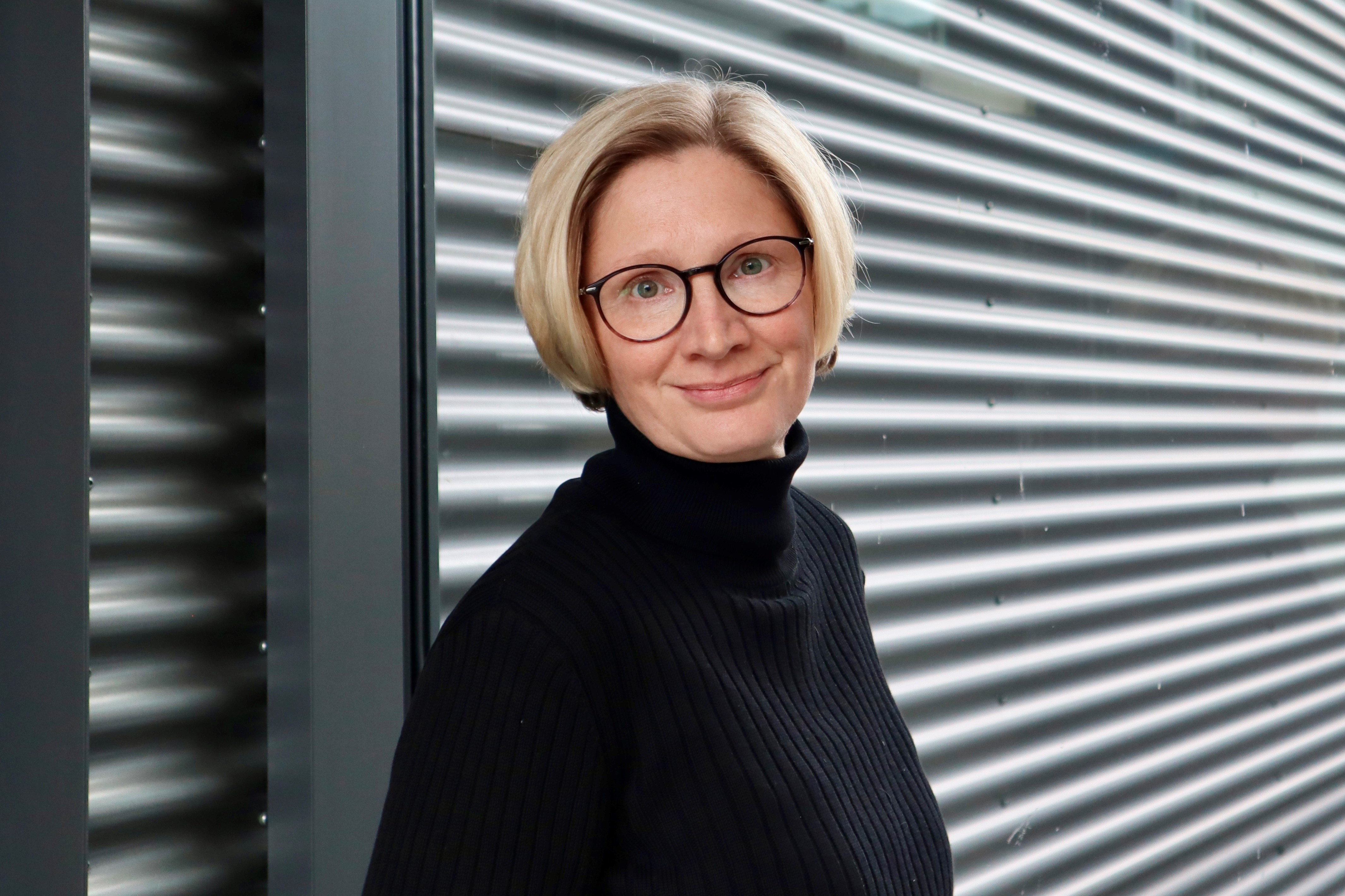 Frau steht vor einem Fenster und lächelt