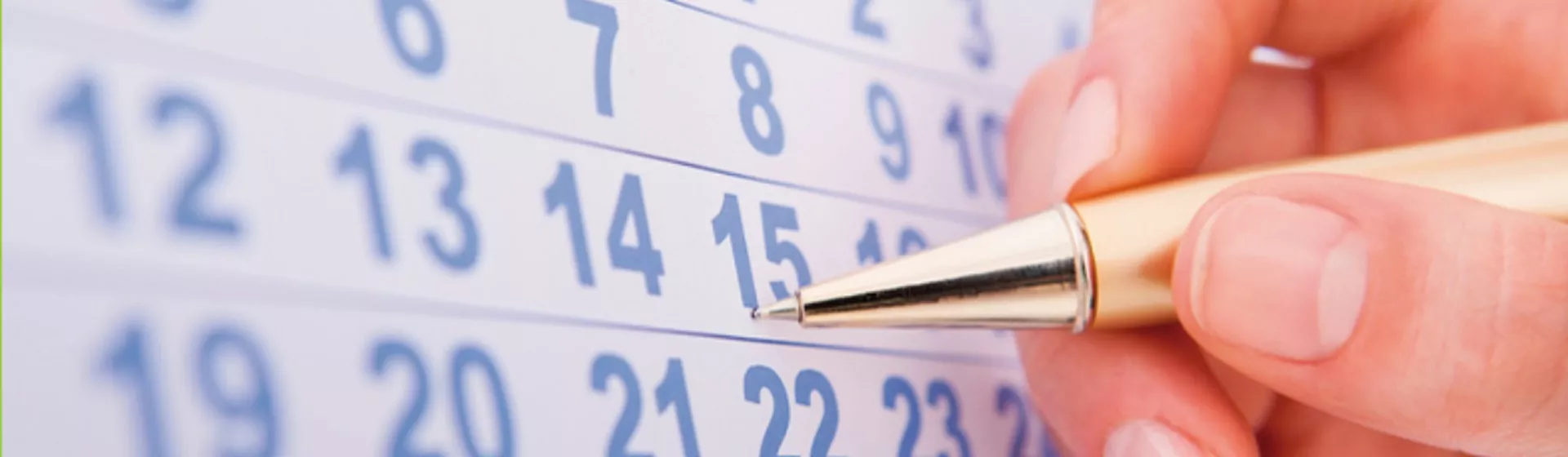 Eine Hand markiert auf einem Kalender ein Datum