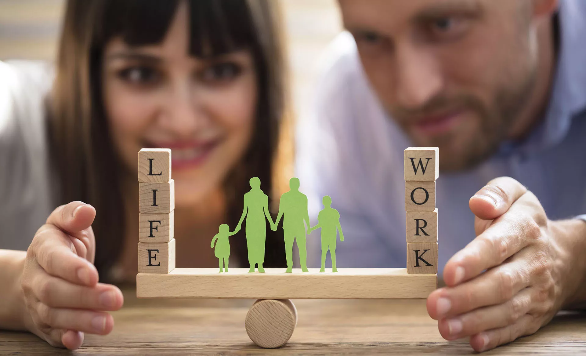 Eine Frau und ein Mann zeigen das Wort Work-Life-Balance mit Hilfe von Spielsteinen.