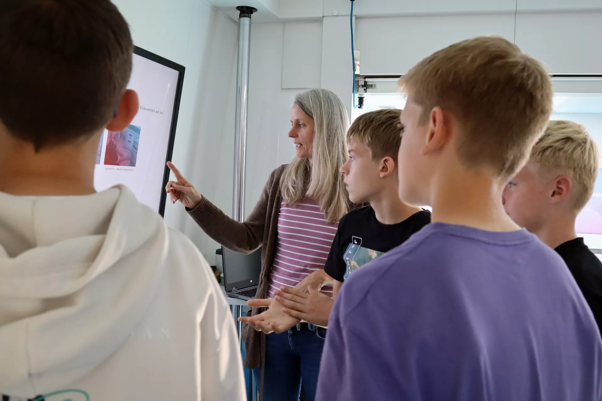 Berufsberaterin zeigt den Jugendlichen etwas auf einem großen Flatscreen