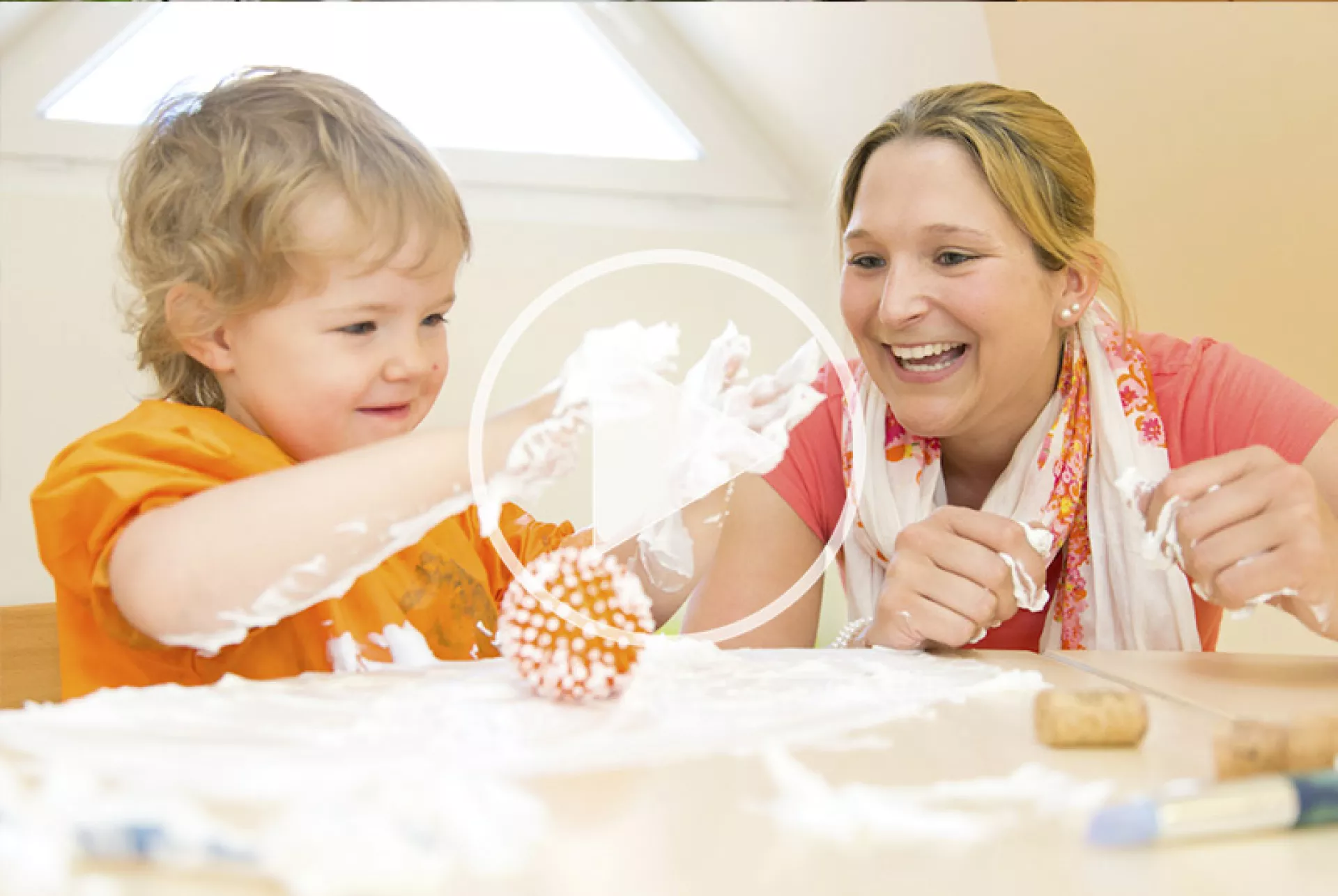 Eine Frau und ein Kleinkind spielen mit Seifenschaum