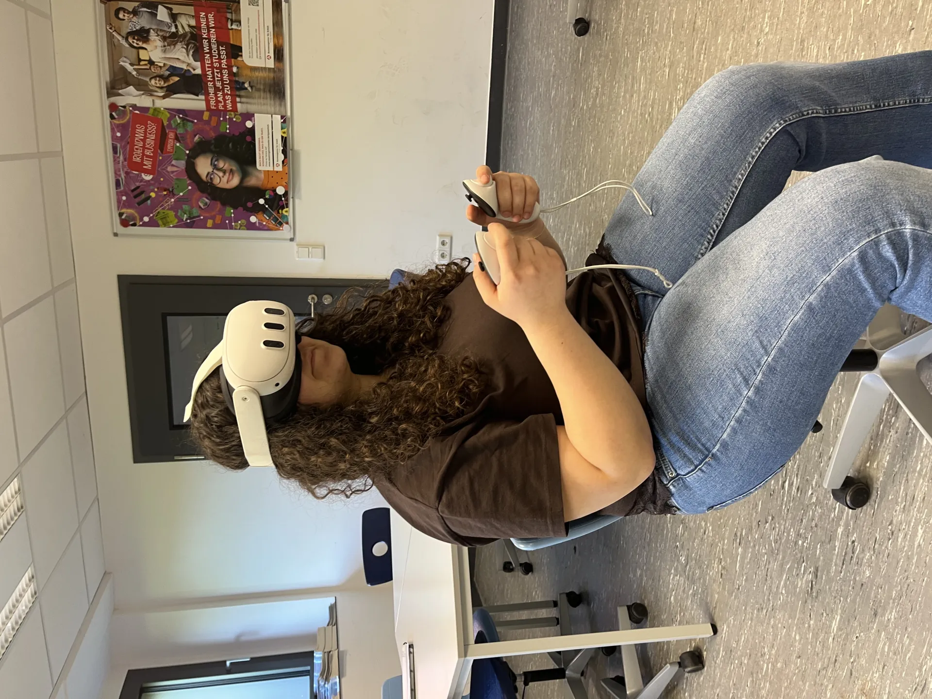 eine Jugendliche sitzt auf einem stuhl und hat eine VR-Brille auf