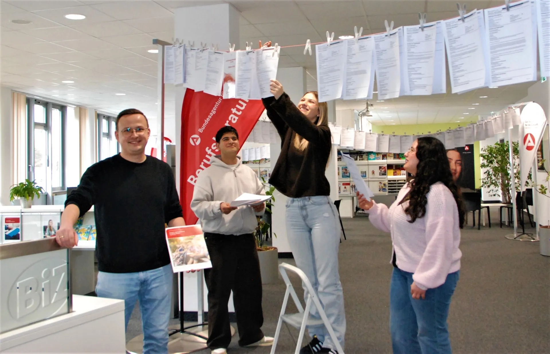 Benedikt Lermer mit den Auszubildenden Jwan Shekho, Lisa Rank und Sudenaz Taylan beim Aufhängen der offen Ausbildungsstellen