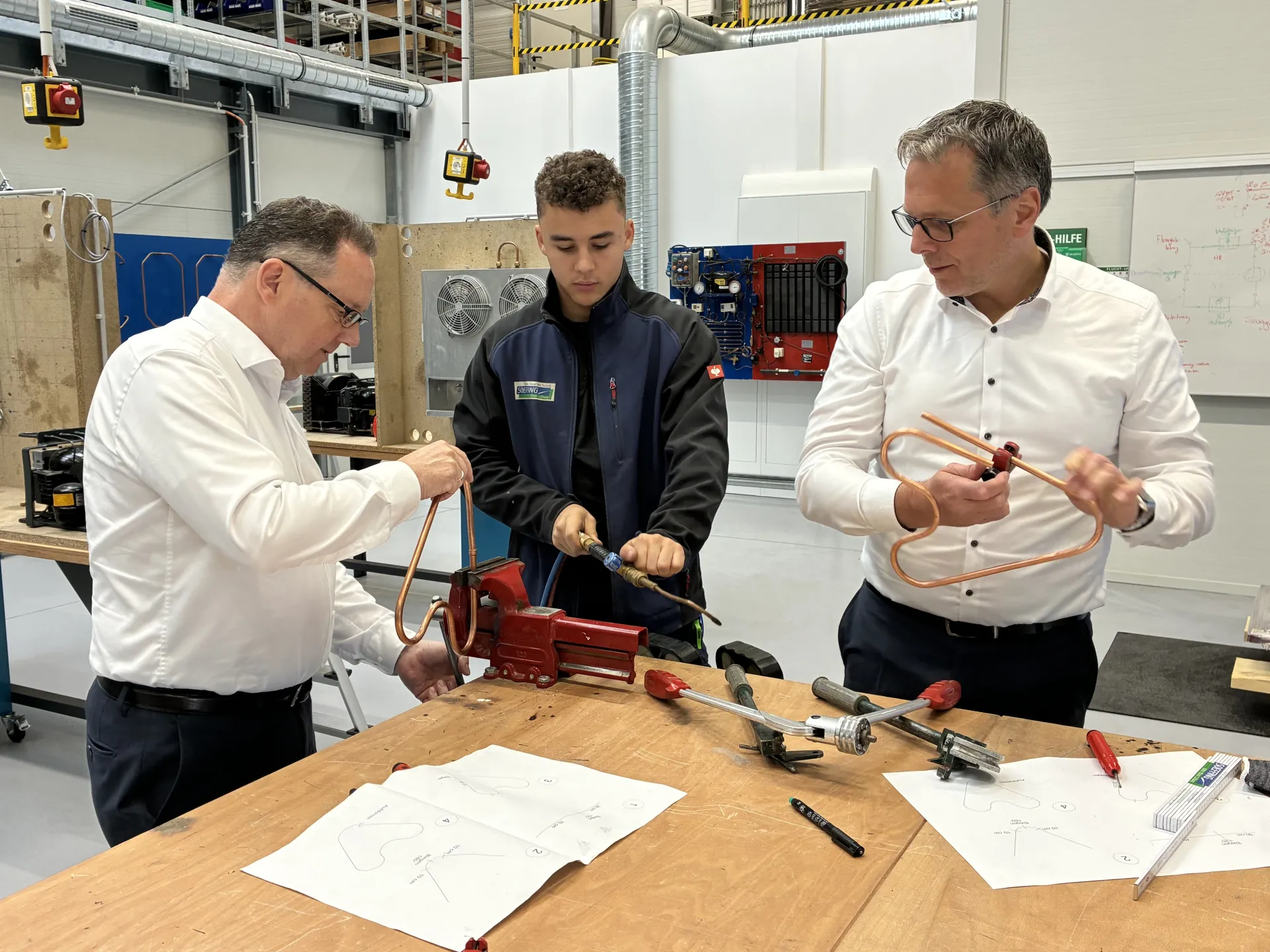 An der Werkbank beim Praktikum zur Kältemechatronik (v.l.n.r.): Karl Tymister (Agentur für Arbeit Mettmann), Azubi Konstantin Ho