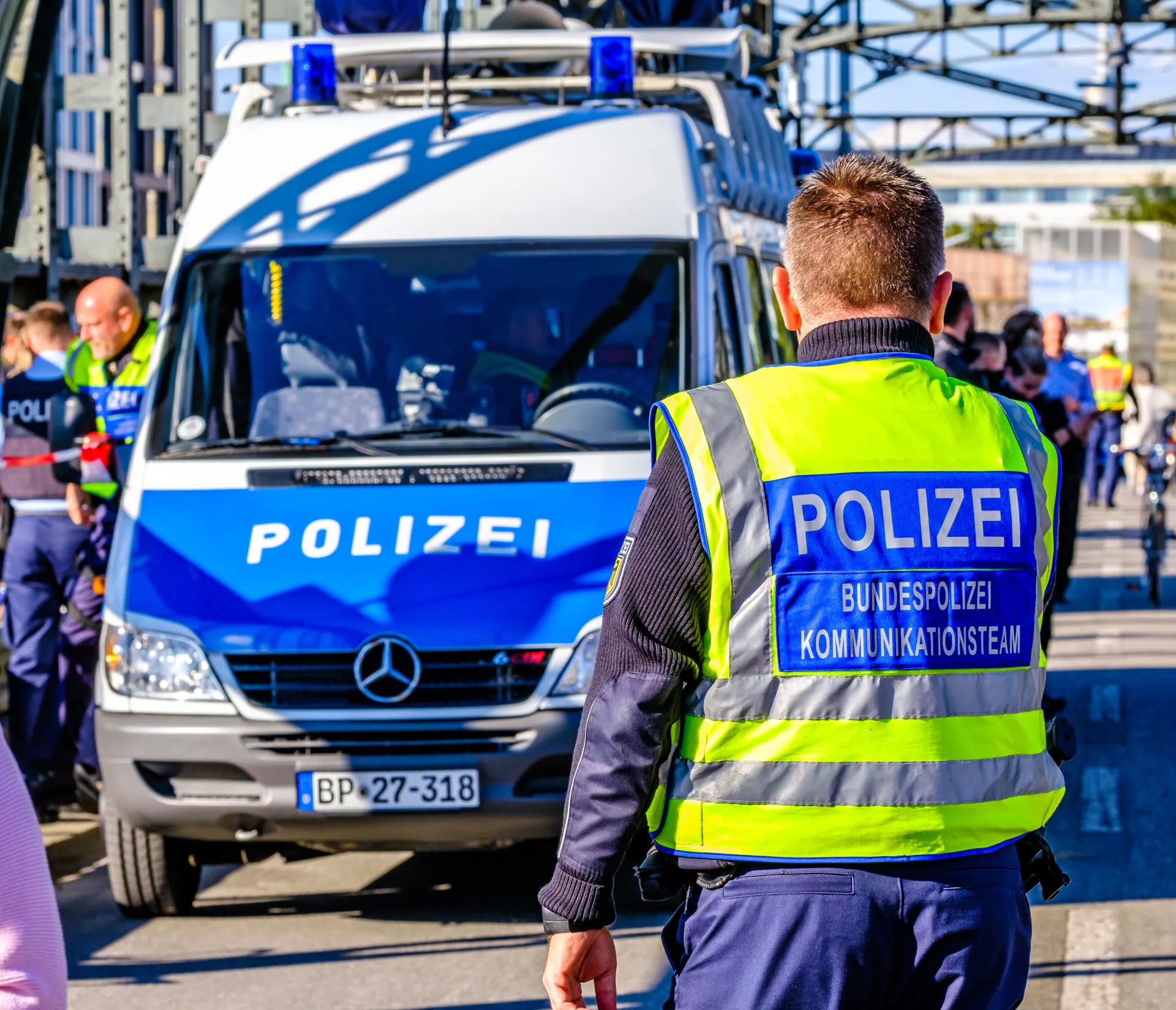 Polizeibus auf einer Brücke mit vielen Polizisten im Hintergrund