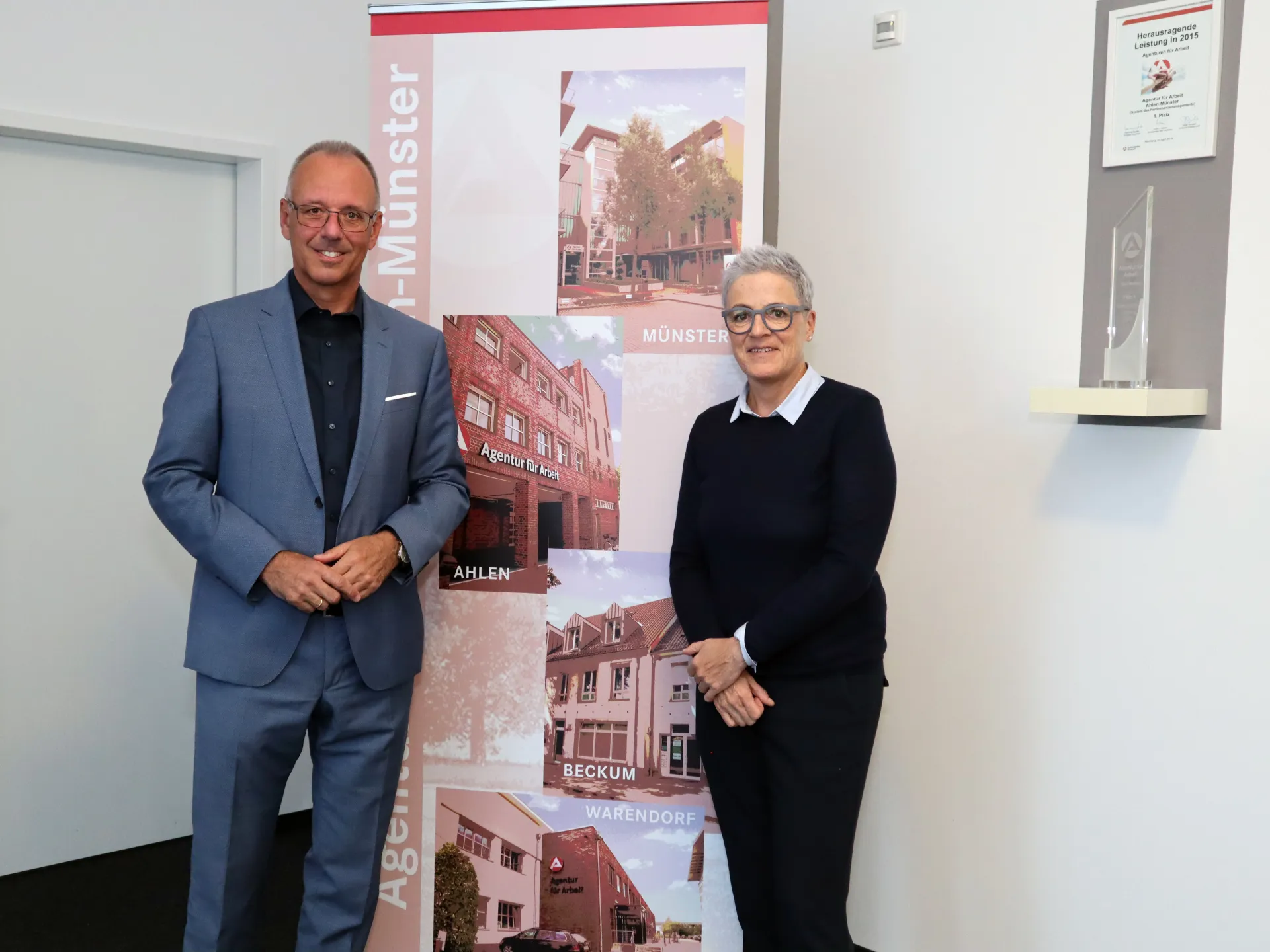 Herr Fahnemann und Frau Rietenberg schauen freundlich in die Kamera