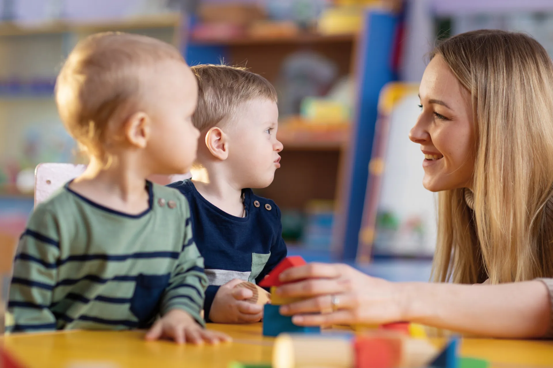 Kindergärtnerin spielt mit zwei Kindern Bauklötze