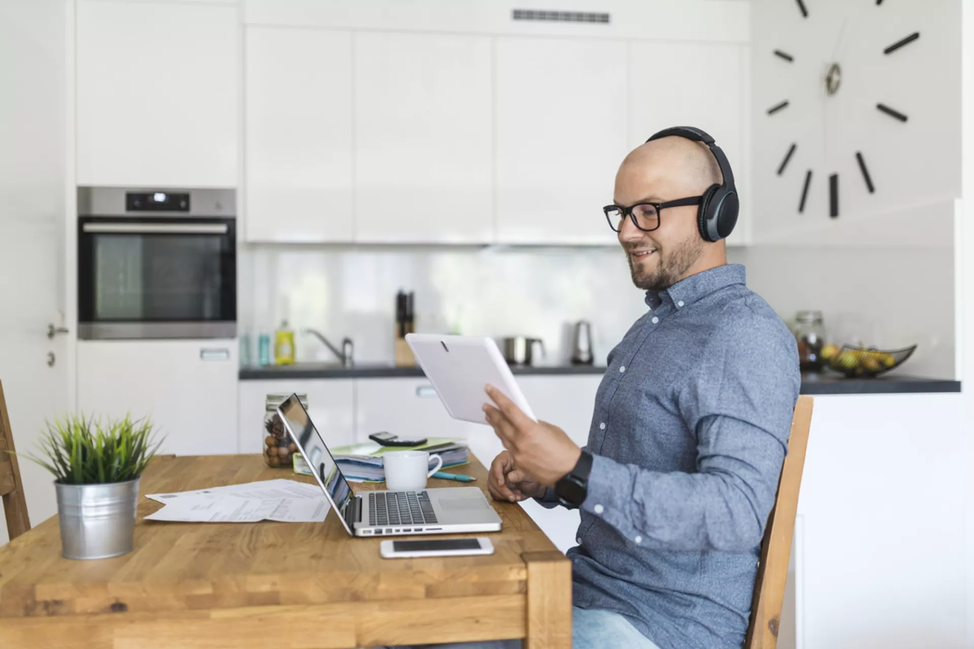 Junger Mann mit Kopfhörern und Laptop im Home Office