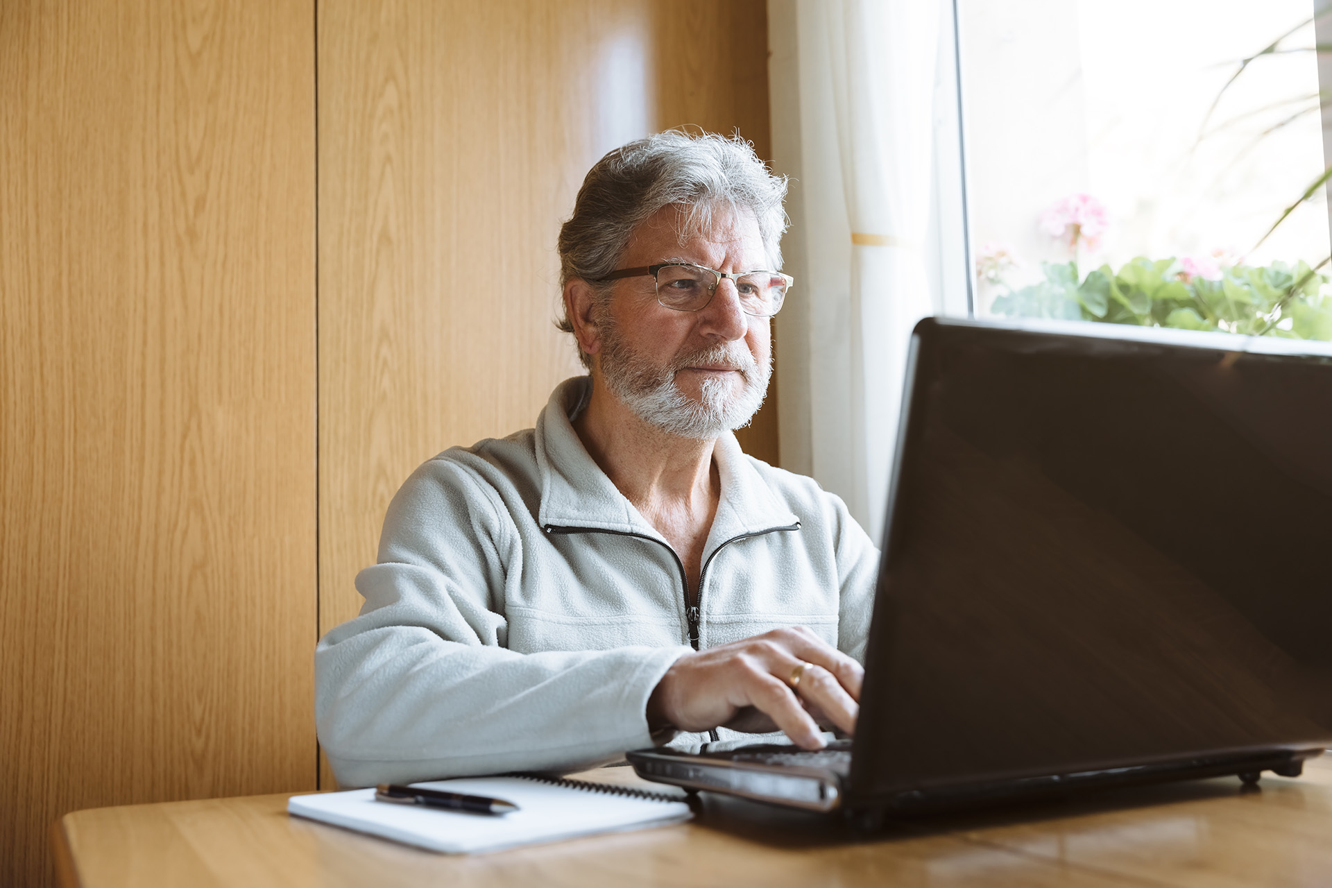 Älterer Mann arbeitet zuhause am Laptop