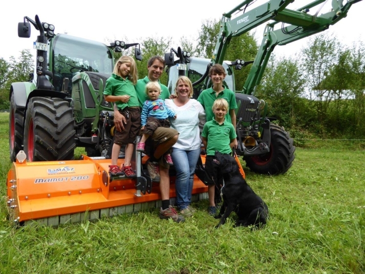 Dominik Jauch mit seiner Familie und Hund vor zwei Landwirtschaftsmaschinen