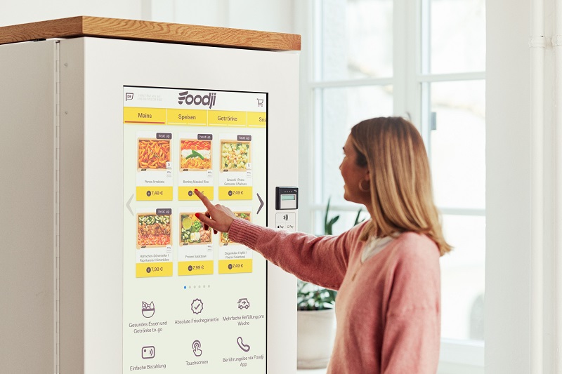 Eine Mitarbeiterin bedient einen Foodji-Essensautomaten