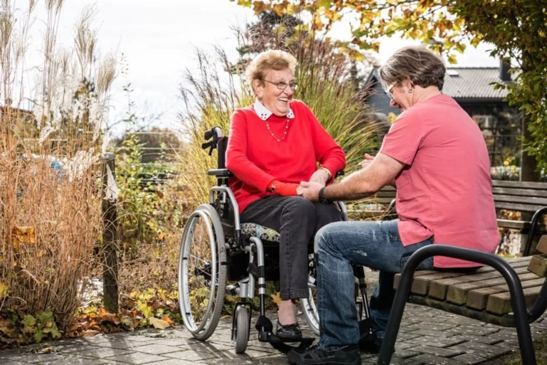 lachende Seniorin im Rollstuhl mit Pflegerin