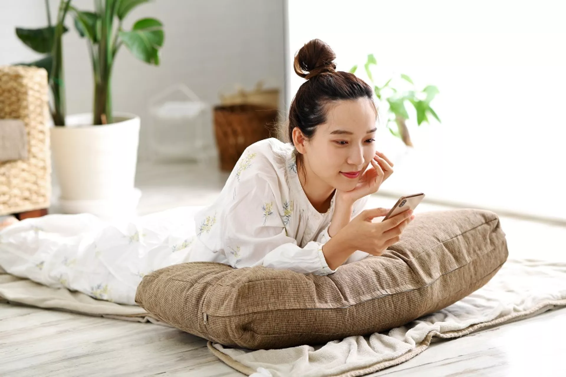 Eine Frau liegt auf einem Kissen mit einem Mobiltelefon in der Hand.