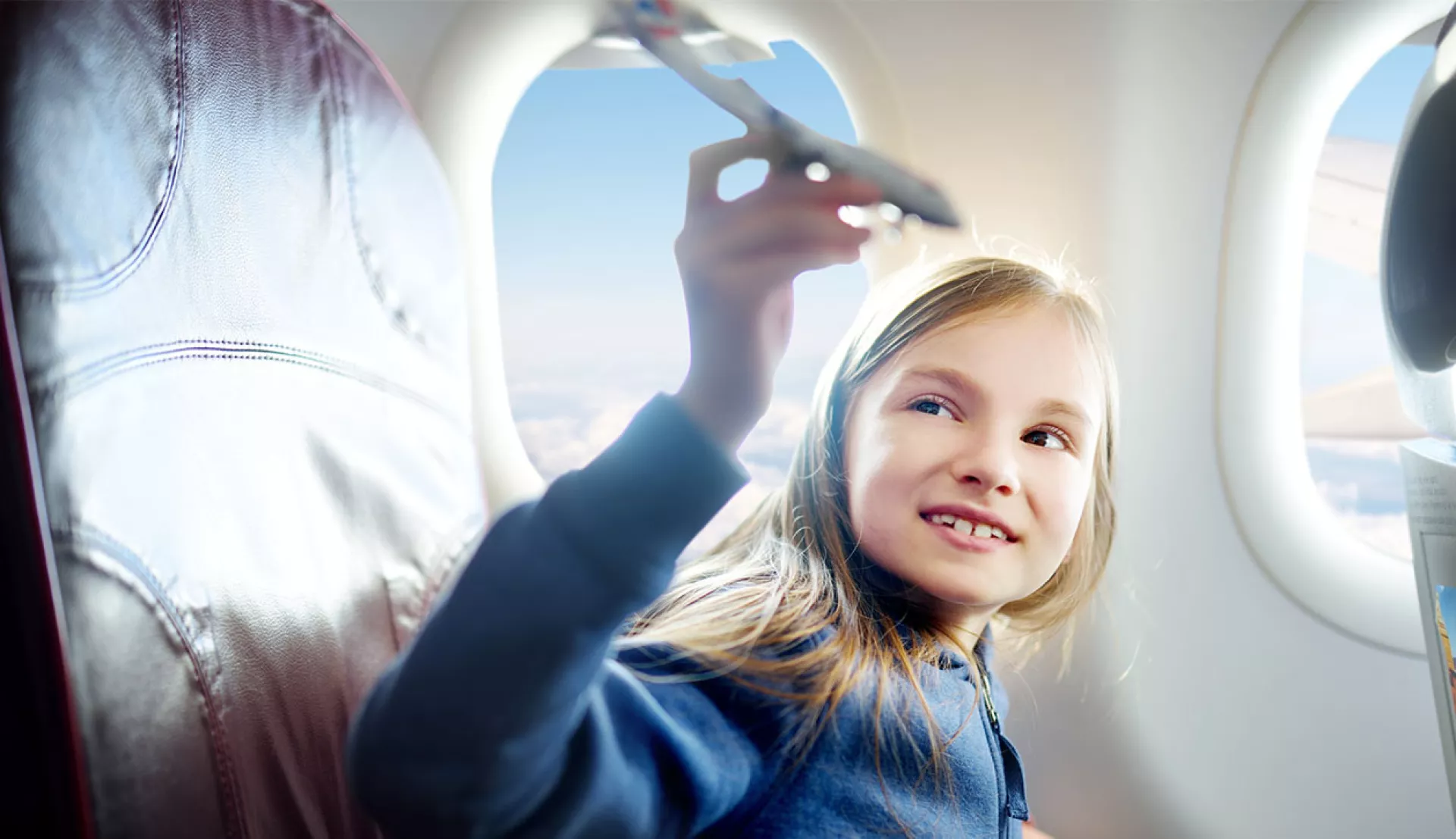 Kleines Mädchen das mit einem Flugzeugmodell in einem Flugzeug spielt