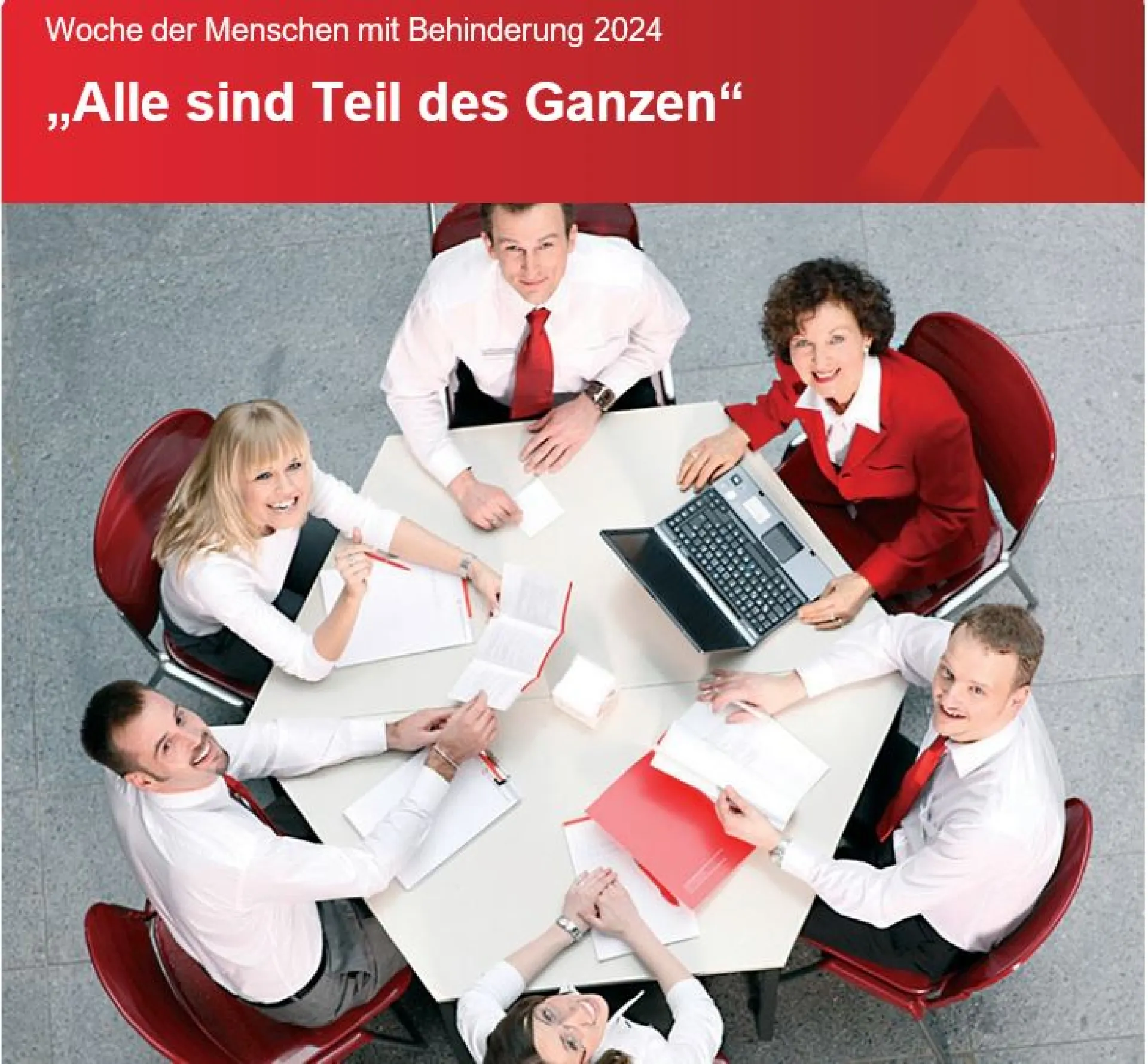 Ein Bild einer Gruppe von fünf Menschen in Business-Kleidung, die an einem runden Tisch sitzen und in die Kamera lächeln. Sie arbeiten gemeinsam an Papieren und einem Laptop. Oben im Bild befindet sich ein rotes Banner mit der Aufschrift: ‘Woche der Menschen mit Behinderung 2024 – Alle sind Teil des Ganzen’.