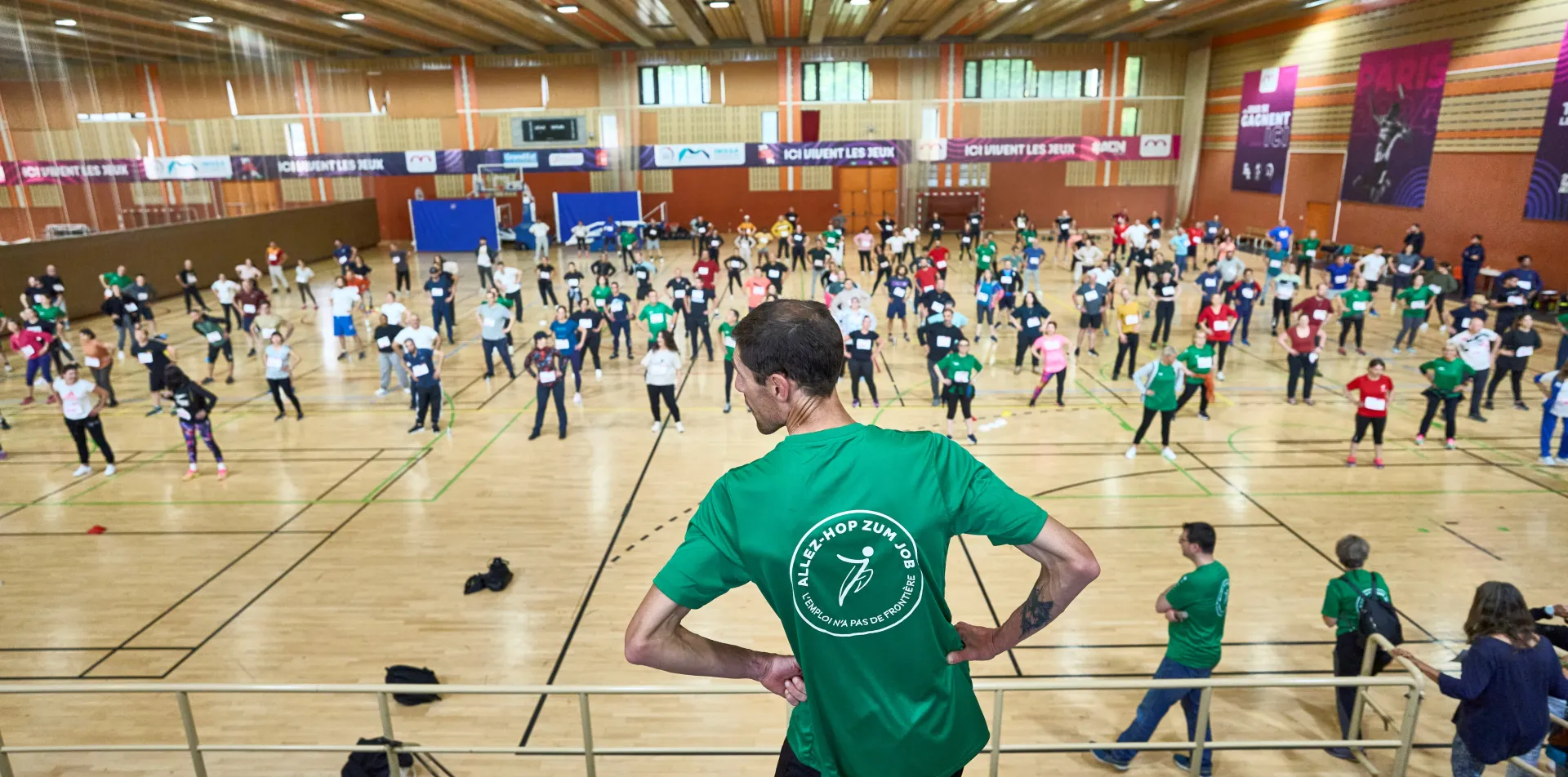 Die Leute trainieren im Sporthalle. Im Vordergrund steht der Coach mit dem Rücken zur Kamera