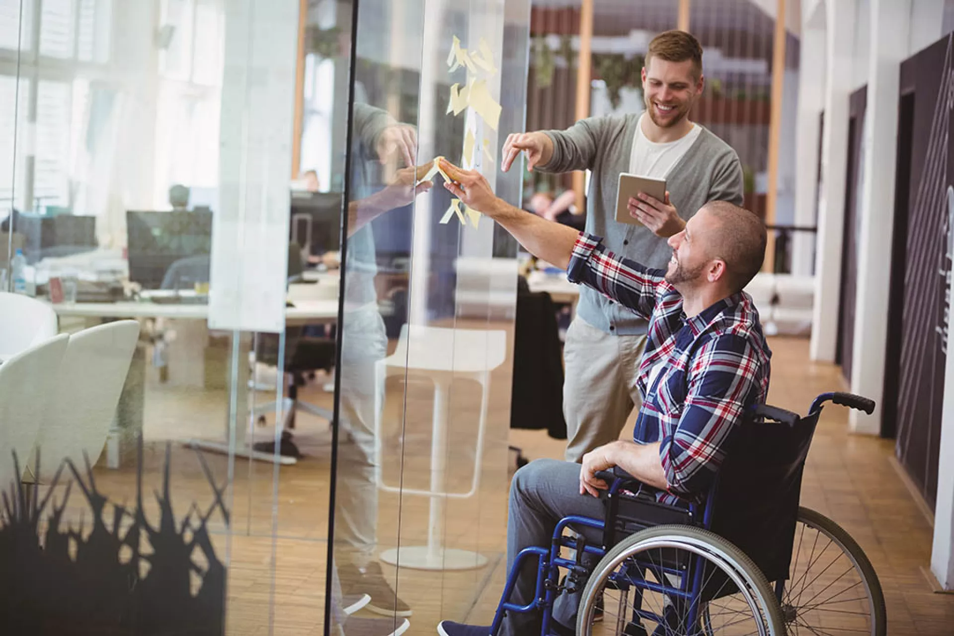 Mitarbeiter mit Behinderung arbeitet in einem modernen Großraumbüro mit Glaswänden