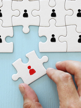 Person fügt letztes Puzzleteil in ein fertiges Puzzle